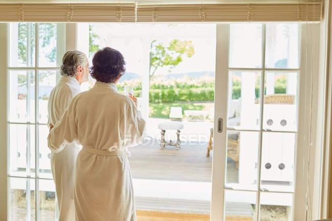 Mature couple in bathrobes at hotel patio doorway — Stock Photo