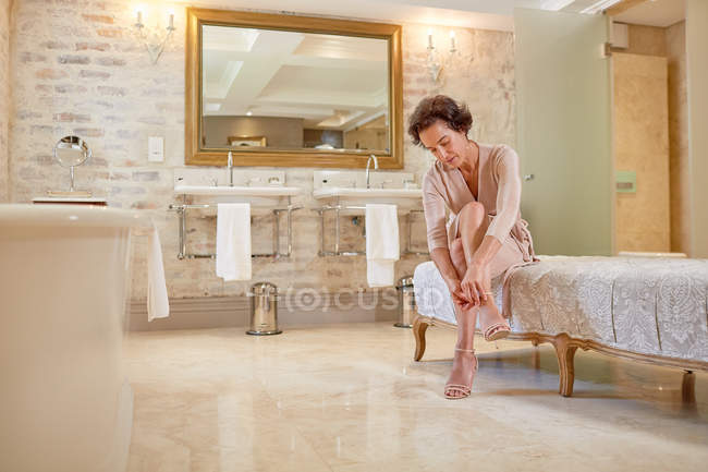 Женщина надевает сандалии на высоком каблуке в роскошной ванной комнате отеля — стоковое фото