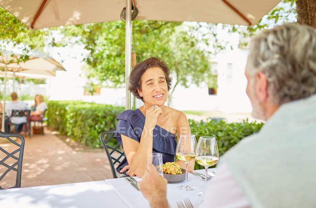 Зрелая пара ужинает за столом в патио курорта — стоковое фото