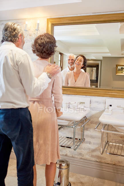 Щаслива зріла пара стоїть у дзеркалі ванної кімнати готелю — стокове фото