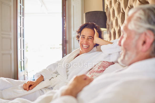Happy, laughing mature couple relaxing on hotel bed — Stock Photo