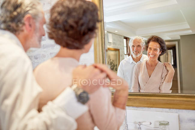 Happy mature couple at hotel bathroom mirror — Stock Photo