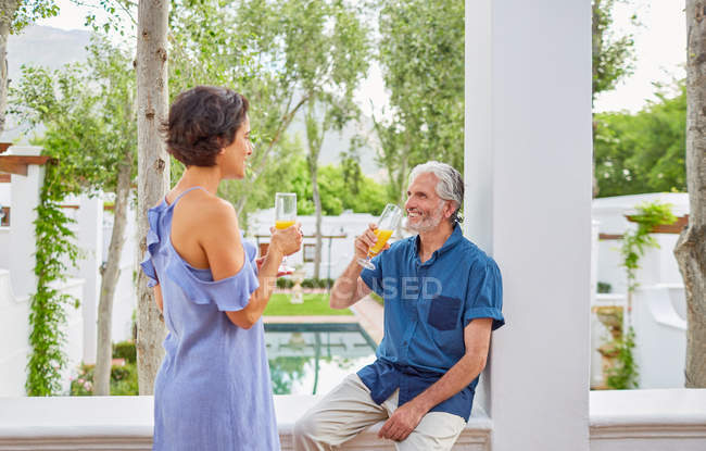 Reifes Paar trinkt Mimosen auf Hotelbalkon — Stockfoto