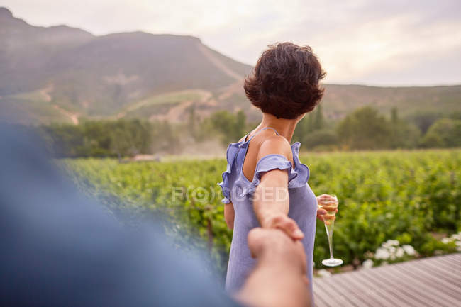 Пара с шампанским, держащимся за руки на патио — стоковое фото