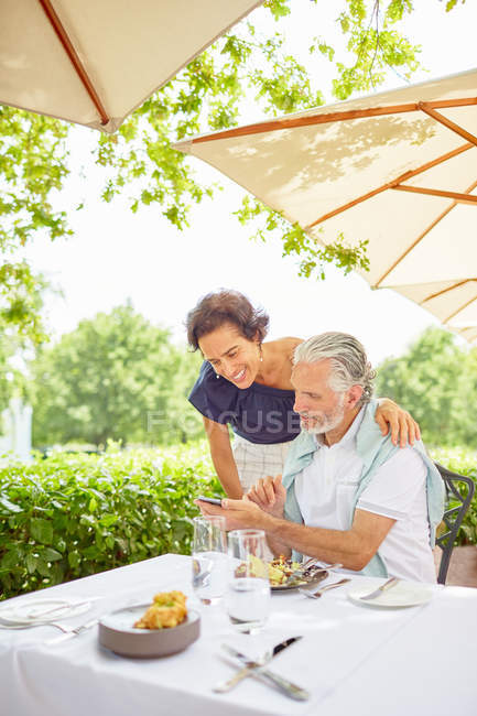 Mature couple with smart phone at patio restaurant — Stock Photo