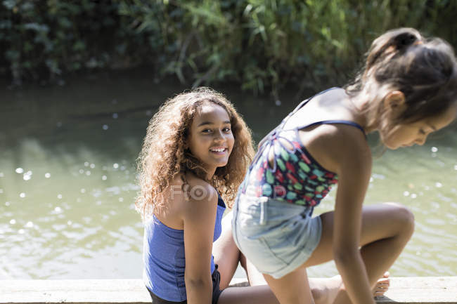Retrato meninas felizes à beira do rio ensolarado — Fotografia de Stock