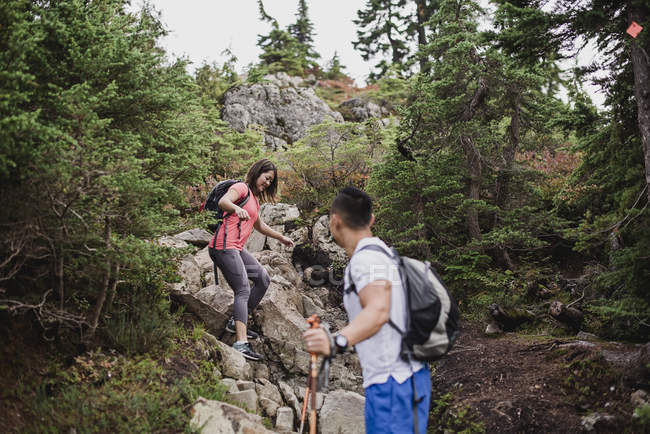 Couple hiking down rocks in woods — Stock Photo