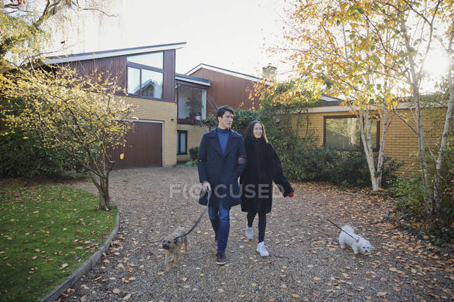 Couple walking dogs in autumn driveway — Stock Photo