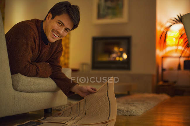 Portrait smiling man reading newspaper in living room — Stock Photo