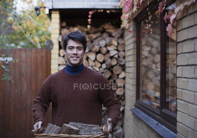 Porträt Mann trägt Brennholz auf herbstlicher Terrasse — Stockfoto