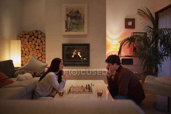 Пара играющая в шахматы в гостиной — стоковое фото