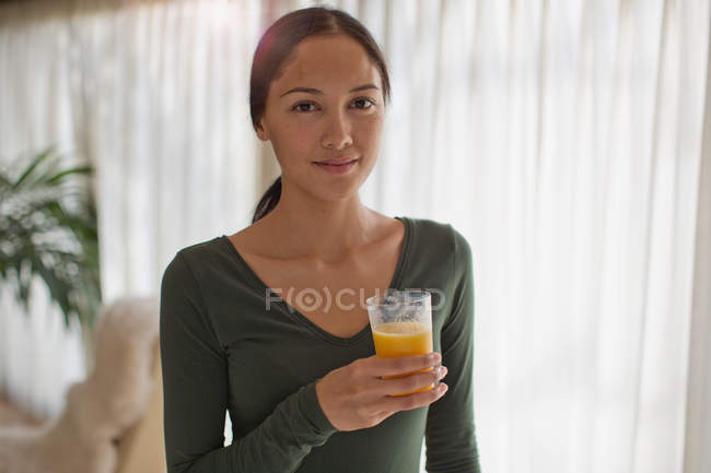 Portrait confident young woman drinking orange juice — Stock Photo