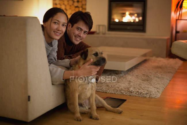 Retrato casal feliz com cão na sala de estar — Fotografia de Stock