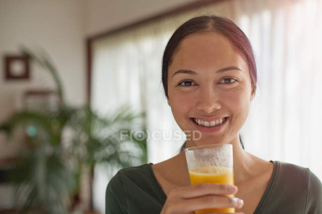 Portrait confident young woman drinking orange juice — Stock Photo