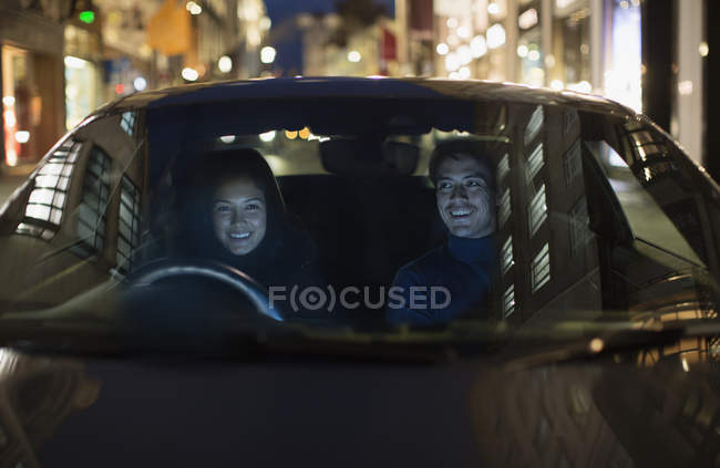 Smiling couple driving on city street — Stock Photo