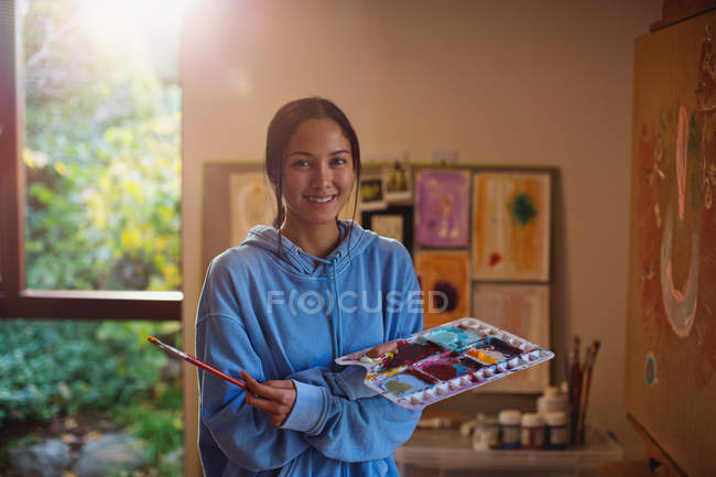 Portrait smiling female artist painting in art studio — Stock Photo