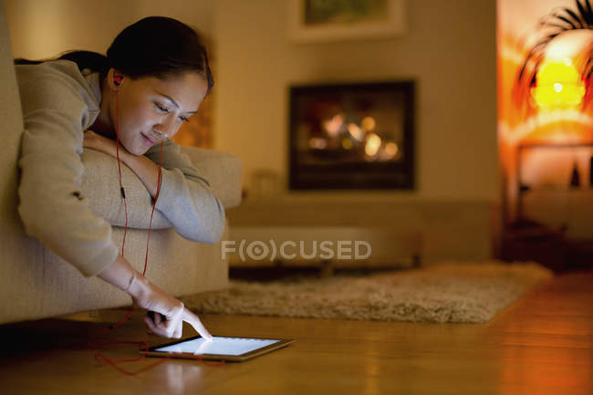 Young woman with headphones using digital tablet in living room — Stock Photo