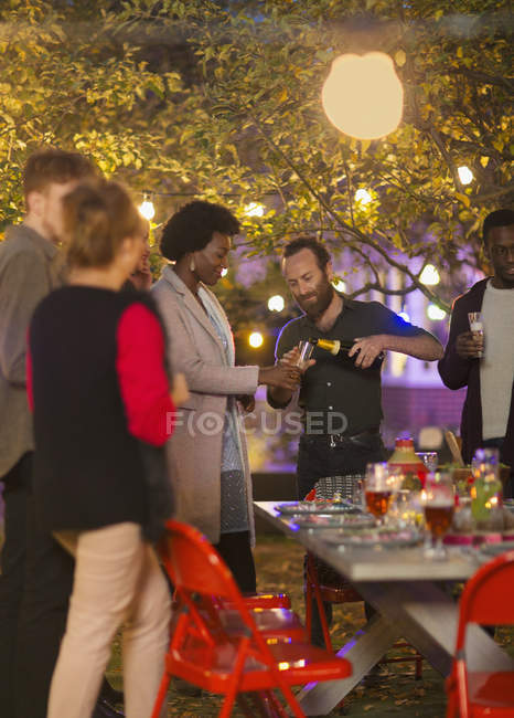 Amigos celebrando con champán en la fiesta del jardín de la cena - foto de stock