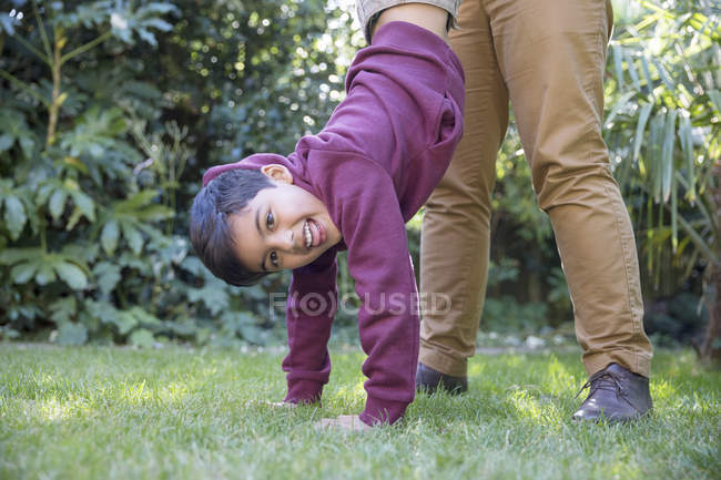 Портрет игривого мальчика висит вверх ногами на заднем дворе — стоковое фото