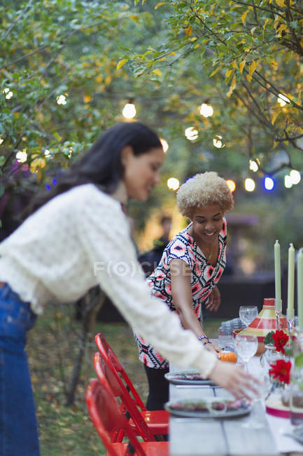 Жінки друзі встановлюють стіл для вечірки в саду — стокове фото
