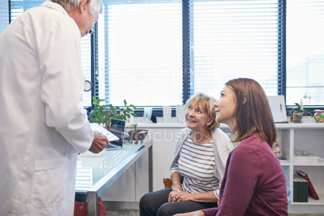 Medico con tablet digitale che parla con le donne nello studio medico — Foto stock