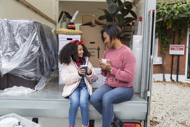 Madre e hija bebiendo té en la parte trasera de la furgoneta - foto de stock
