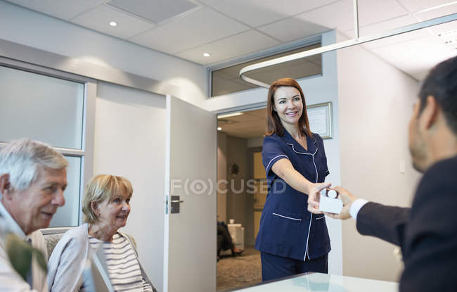 Female nurse giving medication to doctor in clinic doctors office — Stock Photo