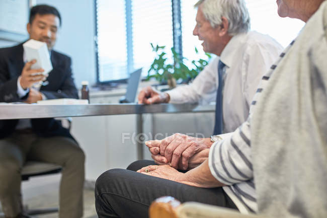 Doctor talking with senior couple in clinic doctors office — Stock Photo