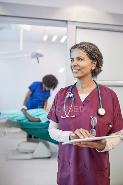 Confident, smiling female doctor with digital tablet in clinic — Stock Photo