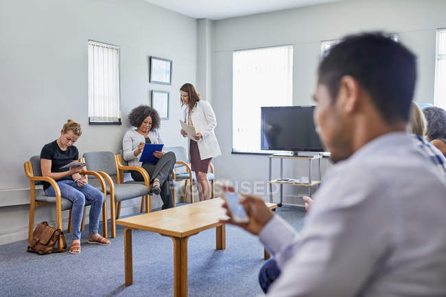 Doctor and patients in clinic waiting room — Stock Photo