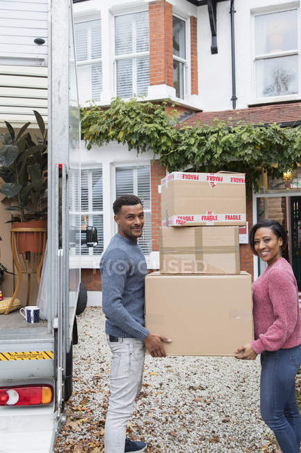 Retrato feliz pareja mudanza casa, llevando cajas de cartón en la entrada - foto de stock