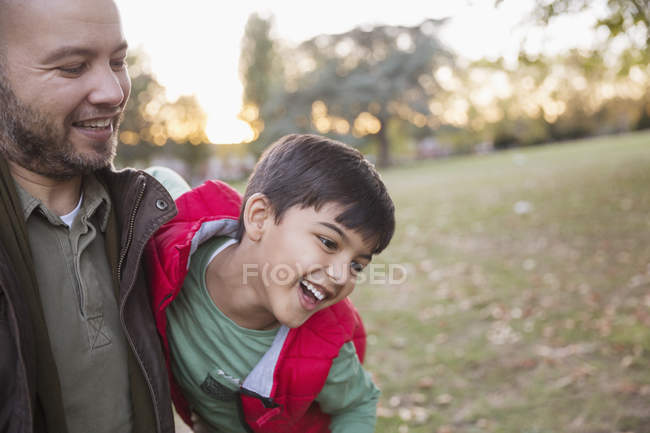 Feliz padre e hijo jugando en el parque de otoño - foto de stock