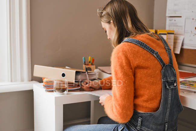 Молодая студентка колледжа учится за столом — стоковое фото