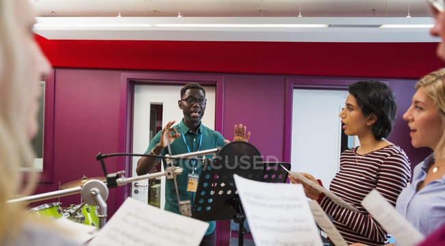 Männlicher Dirigent führt Frauen beim Singen im Tonstudio — Stockfoto