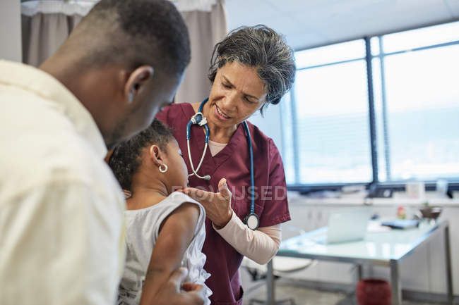 Pediatra femenina examinando paciente niña en sala de examen clínico - foto de stock