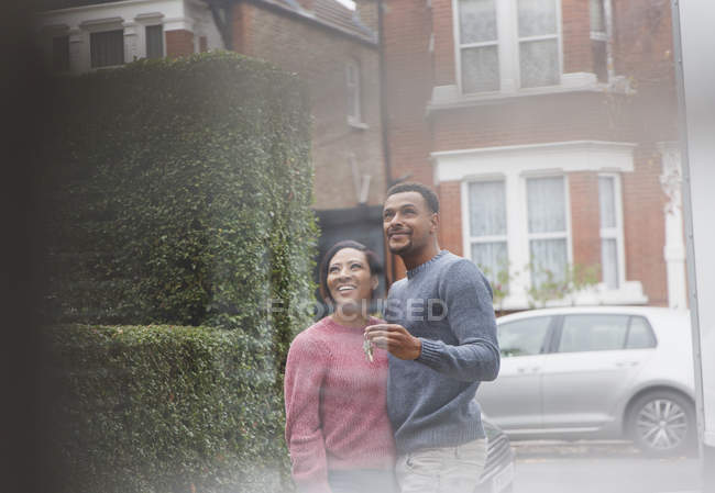 Happy couple with house keys outside new house — Stock Photo