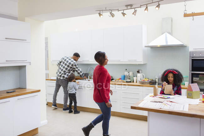 Family doing dishes and making crafts in kitchen — Stock Photo