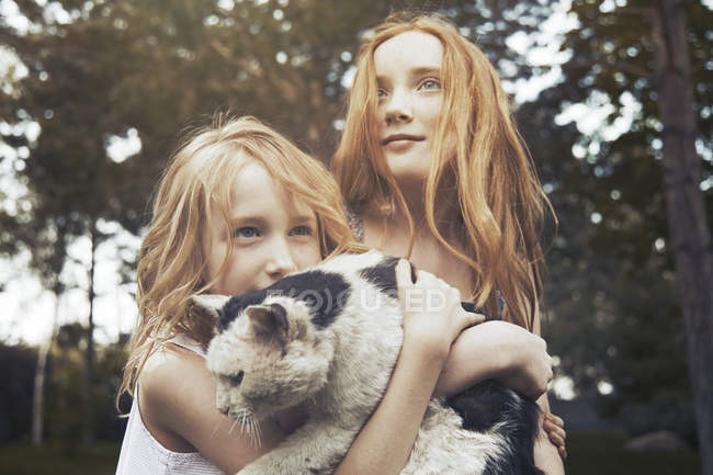 Сестры держат кошку в парке — стоковое фото