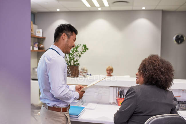Male doctor and receptionist talking in clinic — Stock Photo