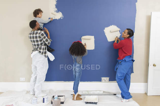 Family painting wall inside new house — Stock Photo