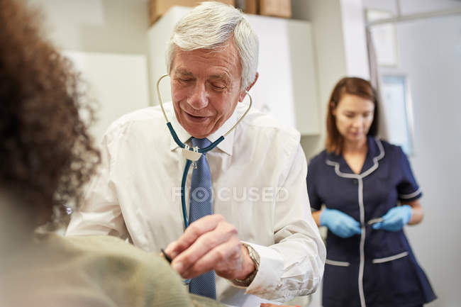 Médecin utilisant le stéthoscope sur le client en clinique — Photo de stock
