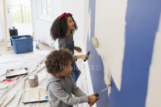 Hermano y hermana pintando pared - foto de stock