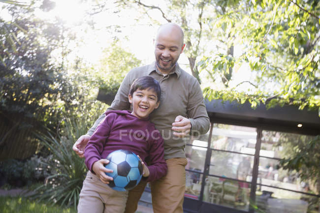 Батько і син грають з футбольним м'ячем на задньому дворі — стокове фото