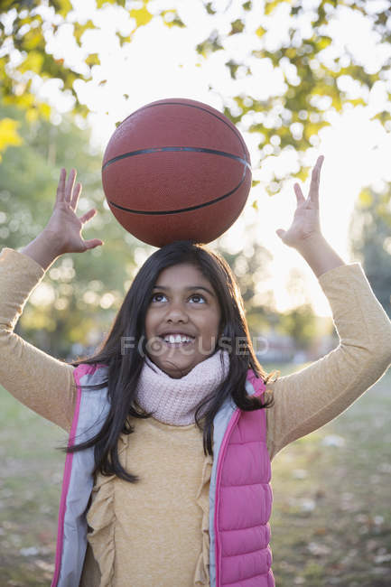 Retrato linda chica baloncesto equilibrio en la cabeza en el parque de otoño - foto de stock