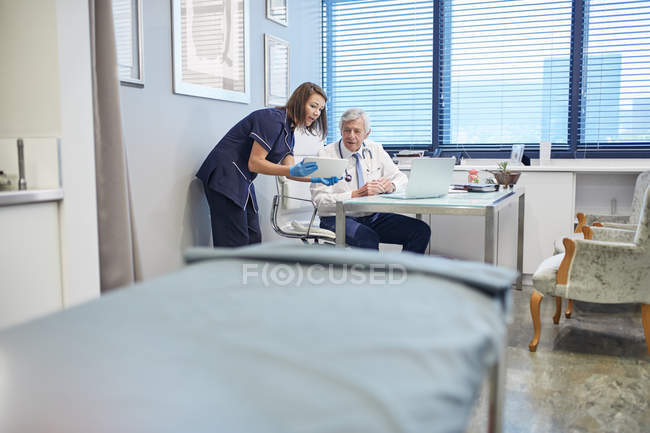 Врач и медсестра с помощью цифрового планшета, консультации в кабинете врача клиники — стоковое фото