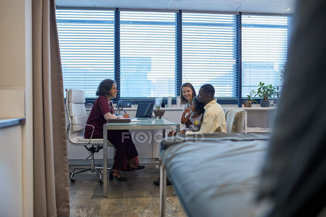 Médico hablando con la familia en el consultorio médico clínico - foto de stock