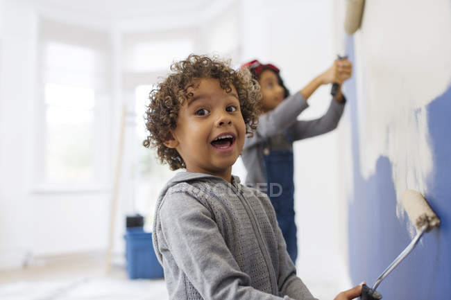 Portrait cute, playful boy painting wall with his sister — Stock Photo