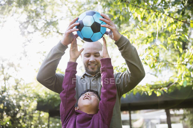 Father and son playing soccer in sunny park — Stock Photo