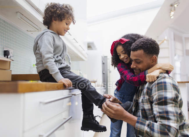 Father tying sons shoe in kitchen — Stock Photo