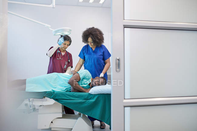 Cirujana y anestesióloga preparan paciente masculino para cirugía - foto de stock